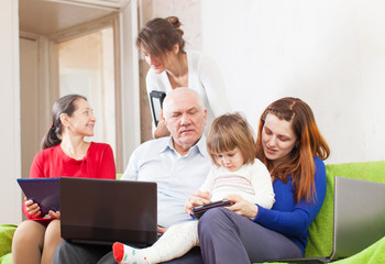 multigenerations family in livingroom room with laptops