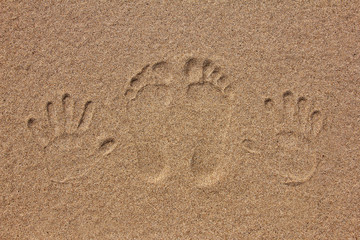 imprint of feet and hand on the sand
