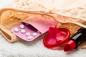 Obraz na płótnie Canvas Pills condom and lipstick on lace lingerie
