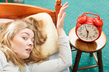Woman waking up turning off alarm clock in morning