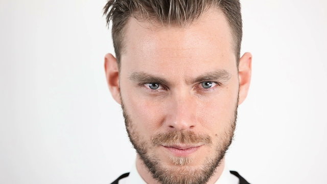 Closeup of a focused man in his 20s with a beard. Intense looking right at camera