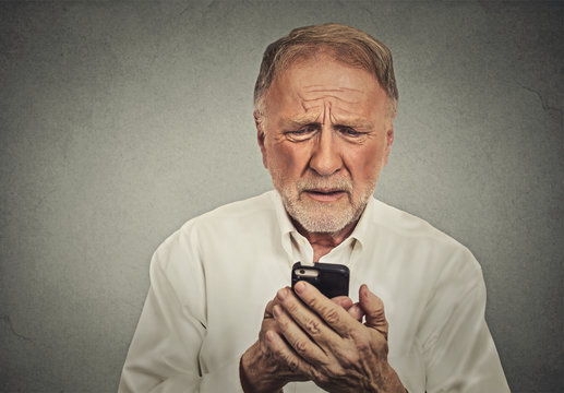 Worried elderly man looking at his smart phone