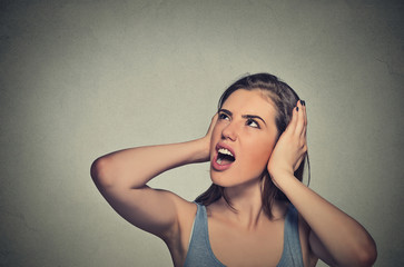 stressed woman covering her ears looking up