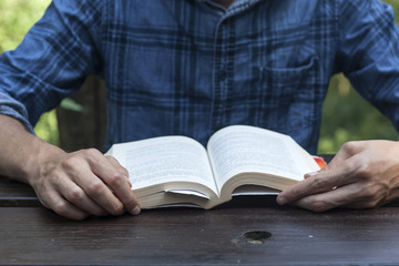 man reading a book on a garden wooden table