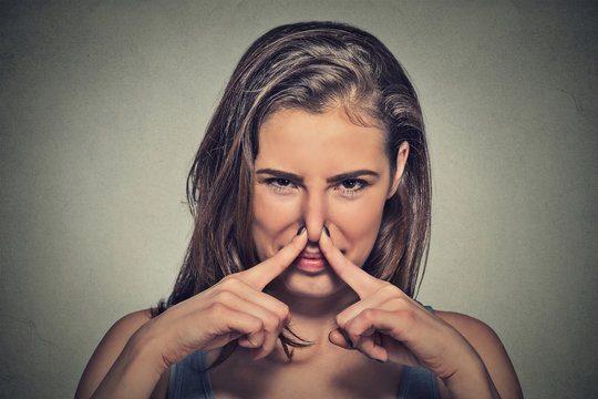 woman pinches nose with fingers looks with disgust something stinks