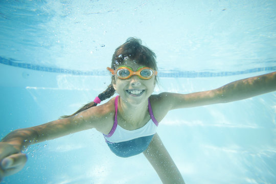 Joyful girl swimming underwater in pool