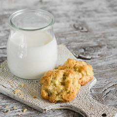 oatmeal cookies with apples and a bottle of milk on a light wooden background