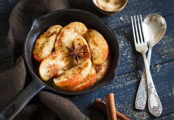 caramelized apples with cinnamon and anise in scourage on a dark wooden background