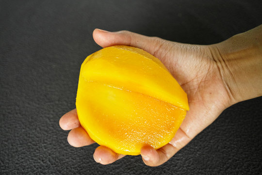 hand with mango isolated on black background