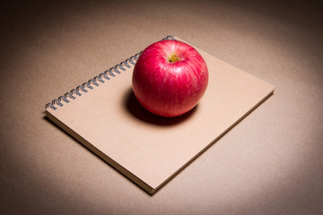 an apple on a brown notebook