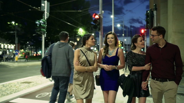Group of people walking at night on street, steadycam shot
