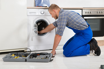 Worker With Toolbox Repairing Washing Machine