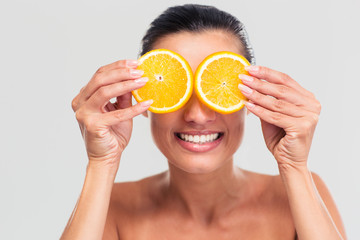 Smiling woman covering her eyes with orange