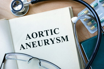 Aortic aneurysm concept. Book with stethoscope and pills.