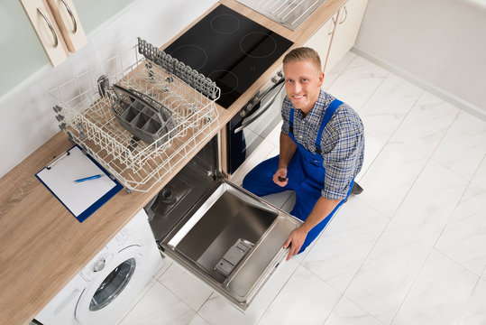 Worker With Toolbox Repairing Dishwasher - Powered by Adobe