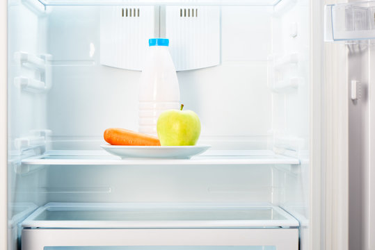 Apple and carrot with bottle of yoghurt in refrigerator