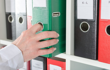 Businesswoman taking a binder from a shelf