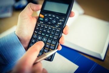 Businessman hands typing on calculator
