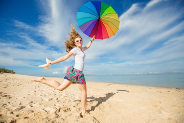 Cheerful young girl with rainbow umbrella having fun on the