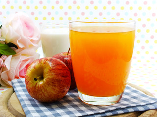 orange juice and red apple on sweet polka dot background