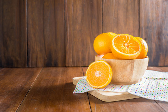oranges in a wooden bowl on wooden background.