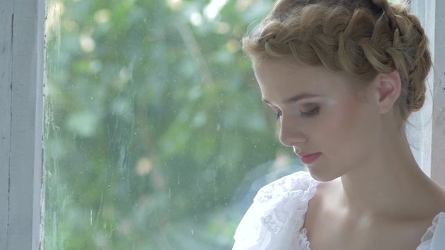 Young blonde girl in white vintage dress smeling flowers, slow