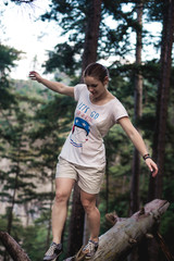 Caucasian hiker woman on trek in mountains living a healthy active lifestyle. Hiker girl on nature landscape hike in Crimea balancing on a tree, happy free female in the wood.