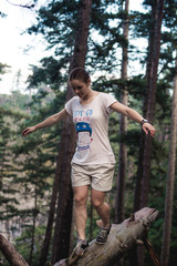 Naklejka na ściany i meble Caucasian hiker woman on trek in mountains living a healthy active lifestyle. Hiker girl on nature landscape hike in Crimea balancing on a tree, happy free female in the wood.