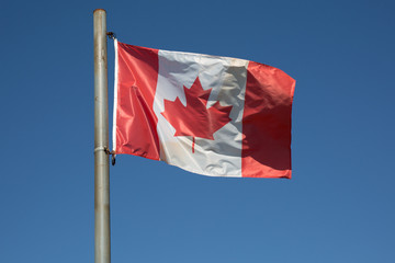 Canadian flag waving in the air over a beautiful blue sky