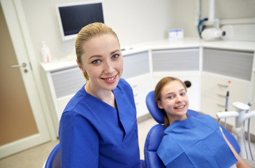 Fototapeta premium happy female dentist with patient girl at clinic