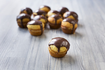Cupcakes with vanilla cream and chocolate topping on grey wood stand