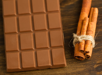chocolate and cinnamon sticks on wooden background