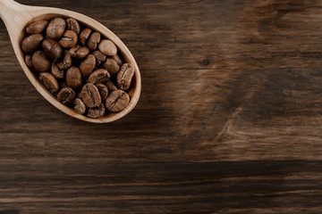 roasted coffee beans in spoon on wooden background