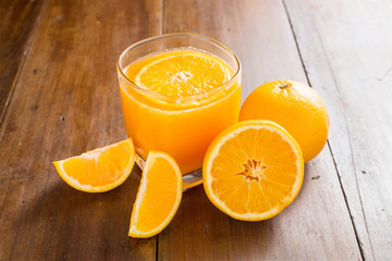 Glass of orange juice with slices on wooden background