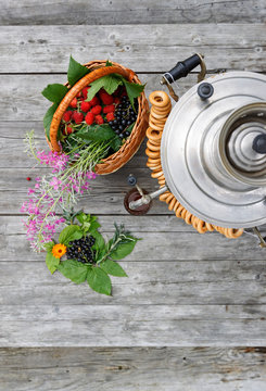 russian samovar on a rustic wooden table with berries and flowers