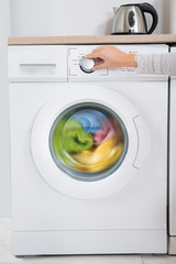 Person Hands Turning Button Of Washing Machine