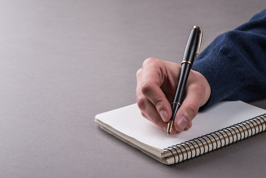 Man writing a note with black ball pen in his hand