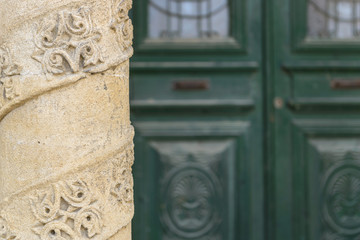 Carved stone pillar with green doors in the background.