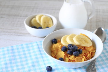 Breakfast cereal with blueberries, bananas and milk on a rustic