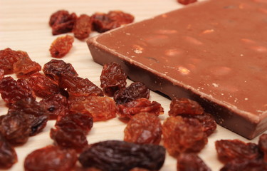 Nutritious chocolate with nuts and raisins on wooden table
