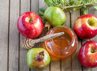 Honey, apples and pomegranates on wood deck for Rosh Hashana celebration.