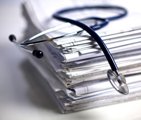 Medical stethoscope rests on a stack of documents