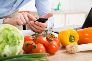 Person Hands Using Mobile Phone In Kitchen