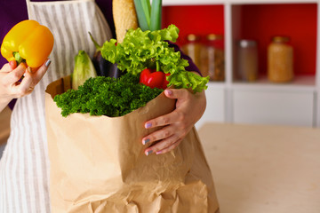 Young woman holding grocery shopping bag with vegetables