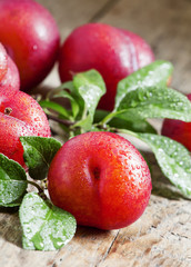 Ripe red plums on old wooden background, selective focus