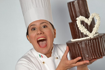 Expresiva y feliz pastelera sujetando un pastel de chocolate.