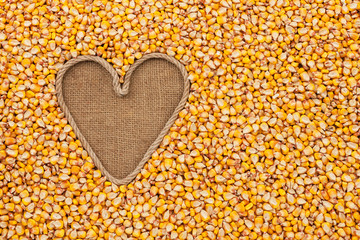 The symbolic heart made of rope lies on sackcloth and maize © alekleks