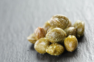 Obraz premium marinated capers in olive bowl on slate board