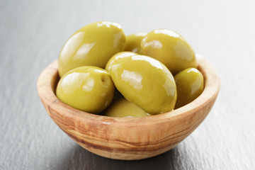pickled giant green olives in olive bowl on slate background