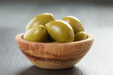 pickled giant green olives in olive bowl on slate background